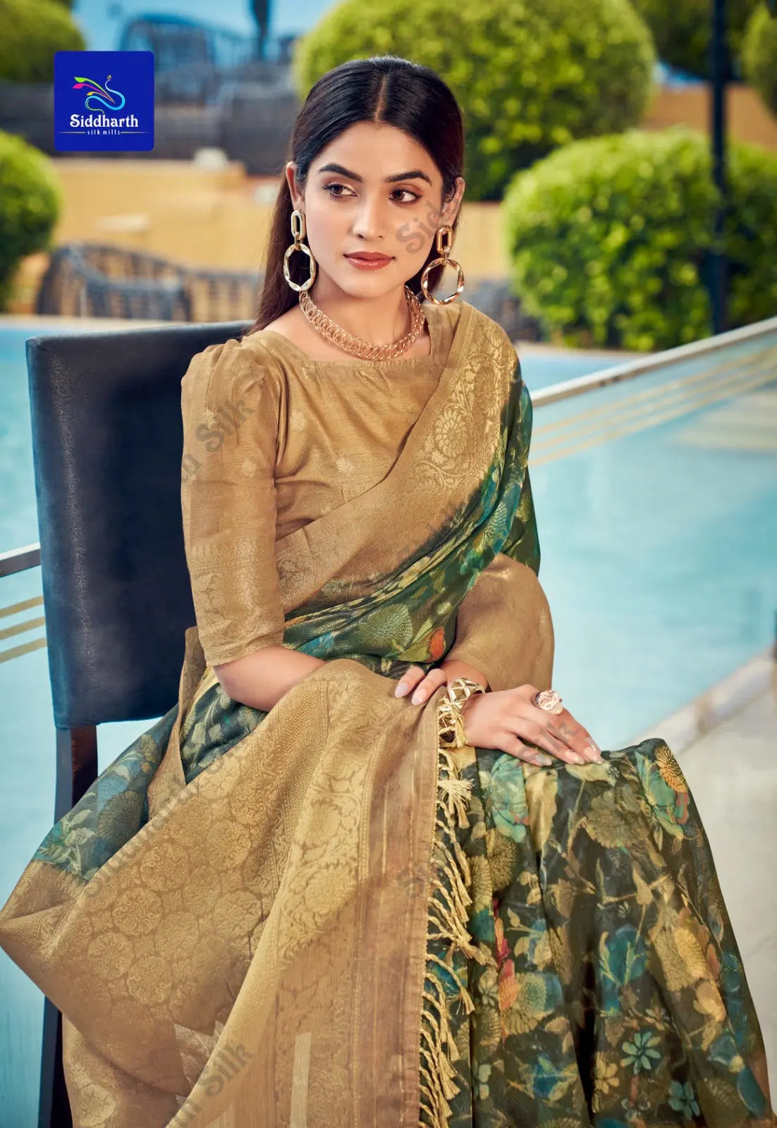 Woman in a dark green zari work saree featuring elegant floral design and rich golden border, posing gracefully by the poolside in ethnic jewelry